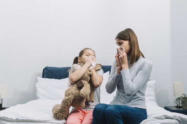 Mother and Her Daughter Blowing Their Noses On A Tissue Paper