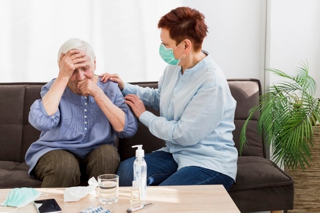 Woman with medical mask taking care of an elder woman